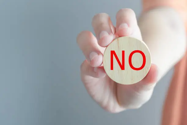 Think With Yes Or No choice.Test question. Choice hesitate, opposition, opponent view. making decision. Woman hand showing No word on wooden circle for expressing rejection or stop symbol.