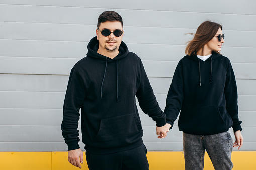Young adult men and woman in glasses and black hoodies