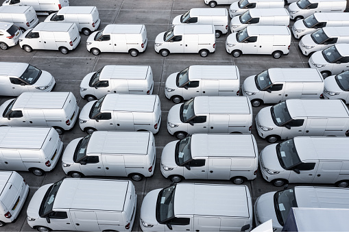 Doncaster, UK - October 13, 2022.  An aerial view directly above rows of new white vans at a vehicle manufacturer ready for onward shipping for export and import