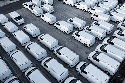 Doncaster, UK - October 13, 2022.  An aerial view directly above rows of new white vans at a vehicle manufacturer ready for onward shipping for export and import