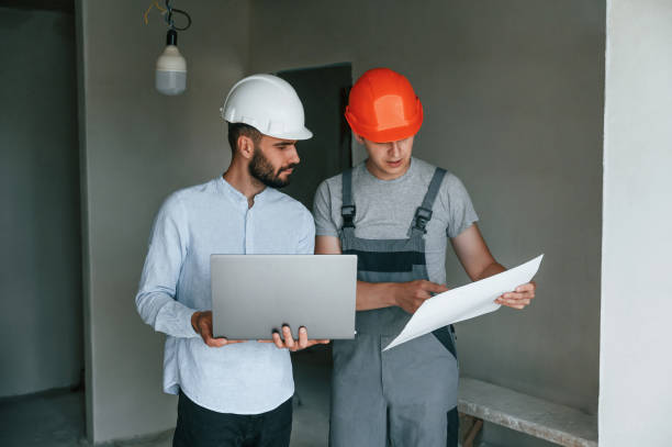 istock Holding laptop and document with plan. Two men is making repairs in the apartment together 1438602934