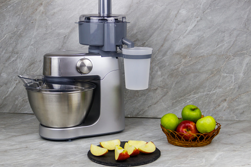Modern electric juicer and apples on a kitchen table
