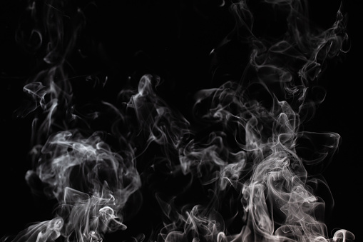 Graphic background with curls of white smoke on a completely black wall. Steam effect.