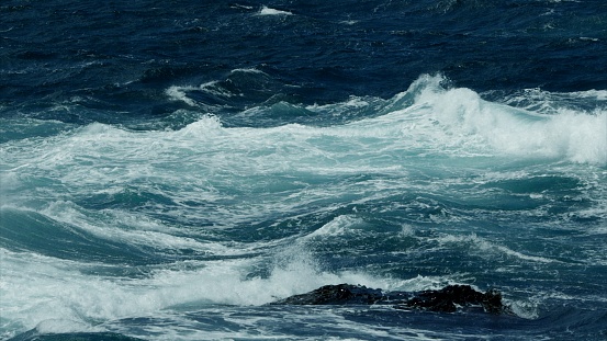 Powerful stormy sea waves shallow water with foam surf. Drone wide shot. Atlantic ocean in climate change on approaching thunderstorm. Bad weather rock shore and hydroelectric power energy concept.