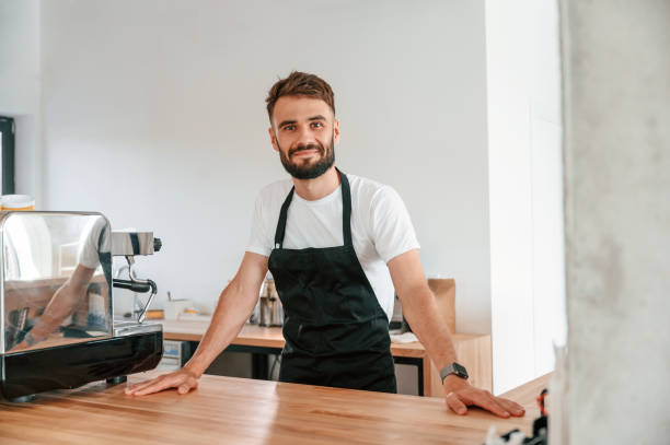 istock Cafe worker in white shirt and black apron is indoors 1438608267