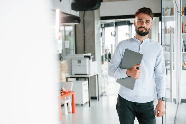 istock With laptop in hand. Young office worker in formal clothes is indoors 1438609713