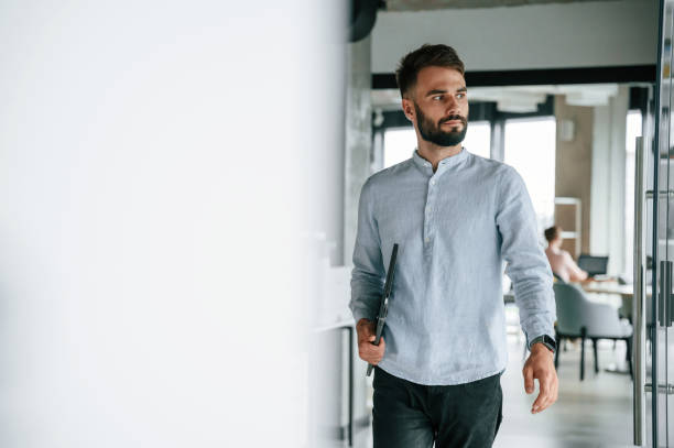 istock With laptop in hand. Young office worker in formal clothes is indoors 1438609742