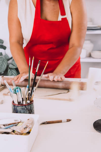 istock Rolling clay with a rolling pin. Cropped image of an unrecognizable female pottery worker working with clay 1438609778