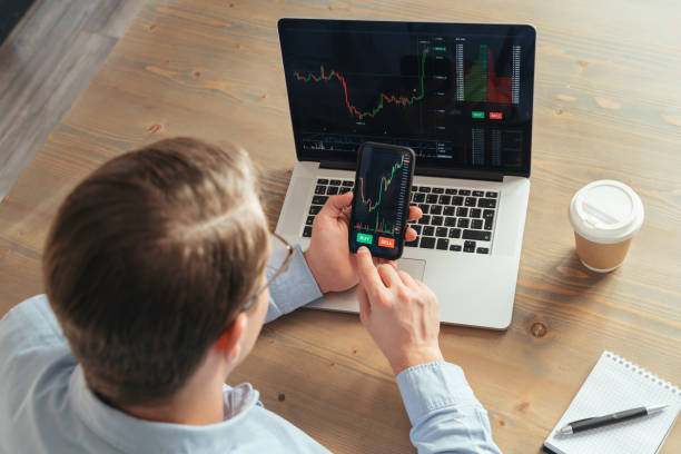 istock Over shoulder top view of man trader investor using mobile phone app for cryptocurrency trading 1438609927