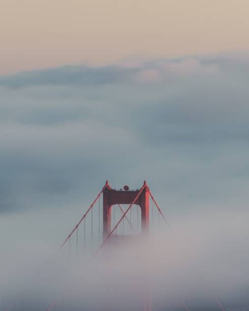 vertikale aufnahme der golden gate bridge umgeben von wolken - san francisco county bridge california fog stock-fotos und bilder