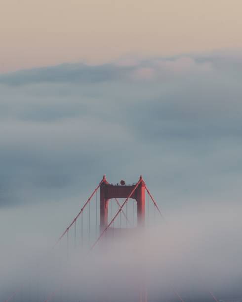 vertical shot of the golden gate bridge surrounded by clouds - san francisco county bridge california fog imagens e fotografias de stock