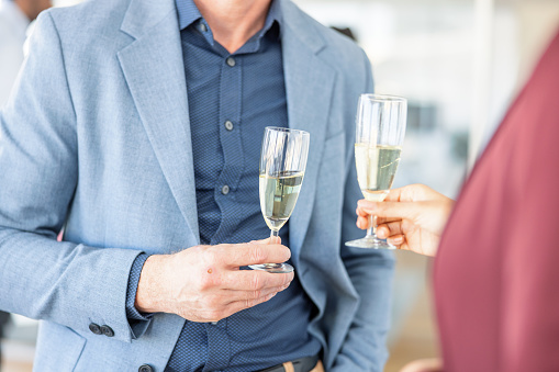 Close up of two office workers toasting with champagne on a celebration day in the office.