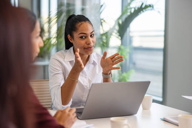 istock Young African-American Woman Explaining A Possible Solution To Her Coworker 1438610721