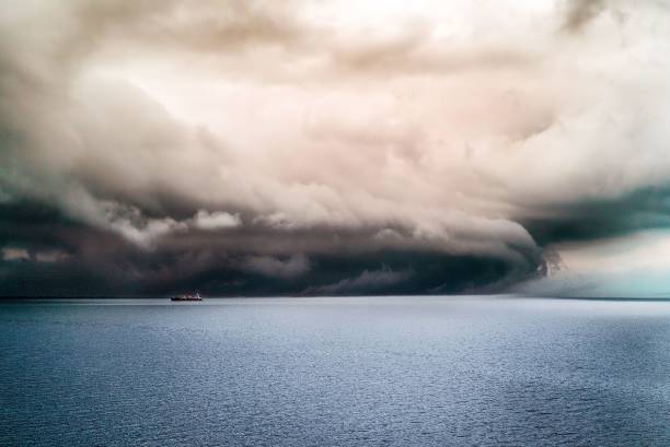 istock Big dark clouds covering the pure ocean with a ship sailing in it 1438611073