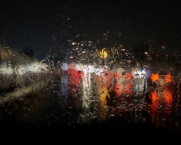 istock Waterdrops on the window blurring the lights outside with a black background 1438611325