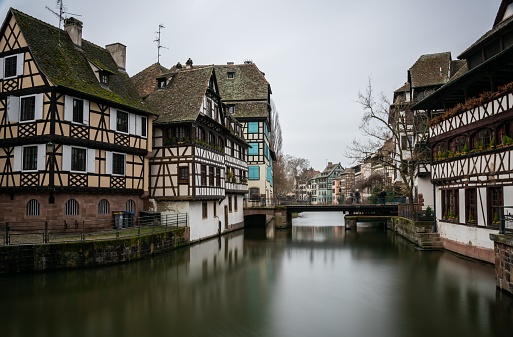 A river surrounded by buildings in Petite France under a cloudy sky in Strasbourg in France