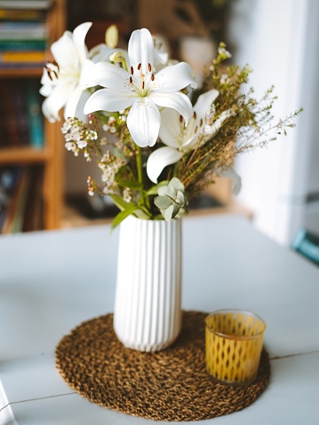 A vertical shot of white orchids in a vase on a table inside a room in Madeira, Portugal