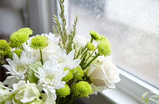A beautiful flower composition with white and green flowers near the window