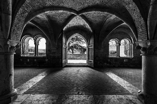 A grayscale shot inside of abbey of saint galgano in tuscany italy with arch walls design