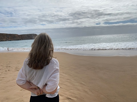 Woman in white dress stretching arms on the beach