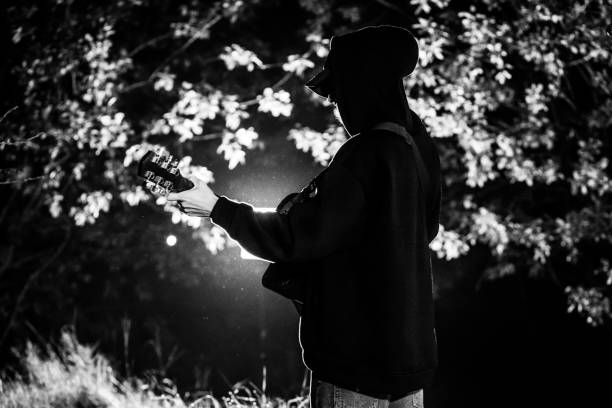 певица играет на акустической гитаре в лесу ночью. заживать - 20s acoustic guitar adult art стоковые фото и из�ображения
