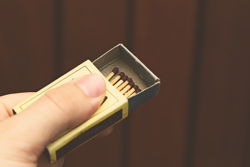 A closeup shot of a person holding an open matchbox with some matchsticks in it
