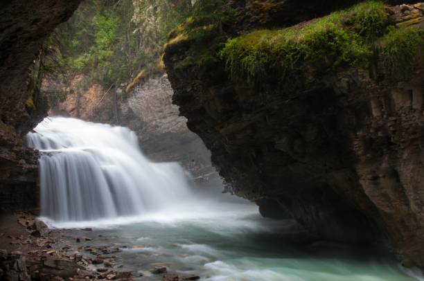 istock Foamy waterfall near the turquoise river under the mossy cliffs 1438614658