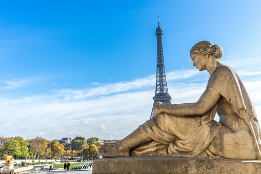 A beautiful shot of the Eiffel Tower behind a statue of a woman