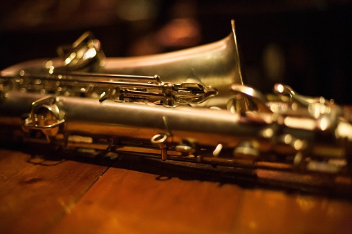 A closeup shot of a baritone saxophone on a wooden table