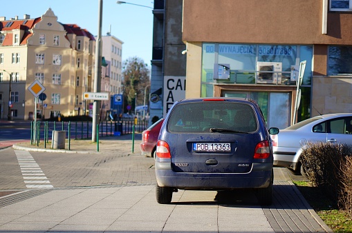 Poznan, Poland – January 16, 2020: Parked blue dirty Renault car on a sidewalk in front of a building.