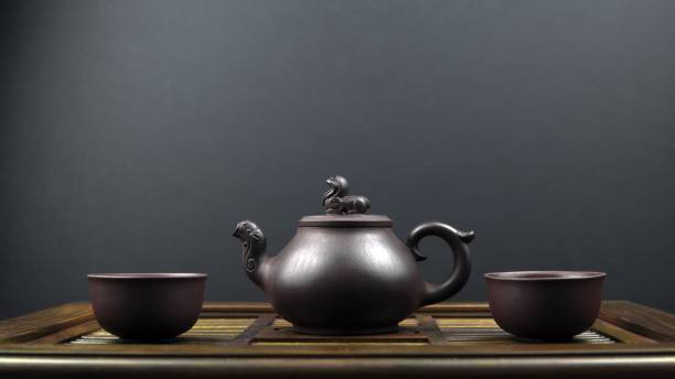 istock Ancient teapot and two clay bowls on a wooden surface with a grey background 1438616660