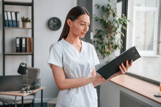 istock Black notepad with documents in it. Young beautiful woman in white clothes is in the office 1438620018