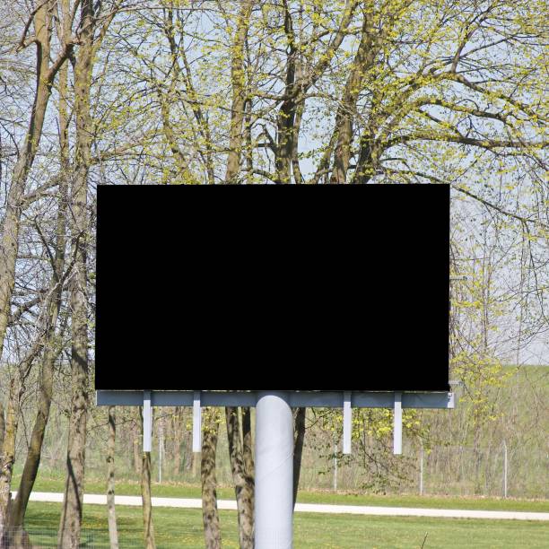 istock Black billboard tv screen with branches of trees in the background 1438620477