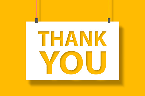Thank you message on paper hanging with rope on yellow background