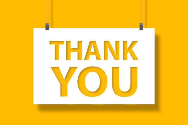 Thank you message on paper hanging with rope on yellow background stock photo