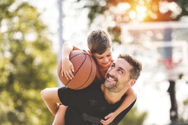 uomo e ragazzo che giocano a basket su un campo, insegnando a un piccolo giocatore e trascorrendo del tempo all'aperto - termine sportivo foto e immagini stock