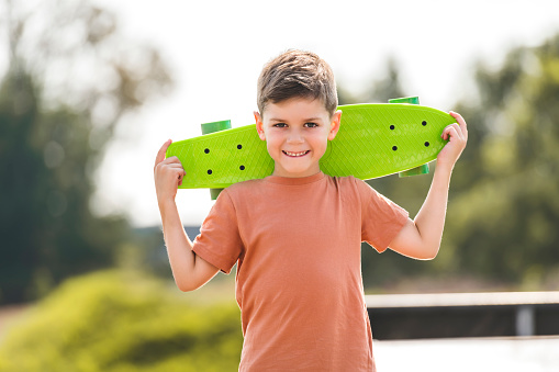 A boy child holds a skate on his shoulders
