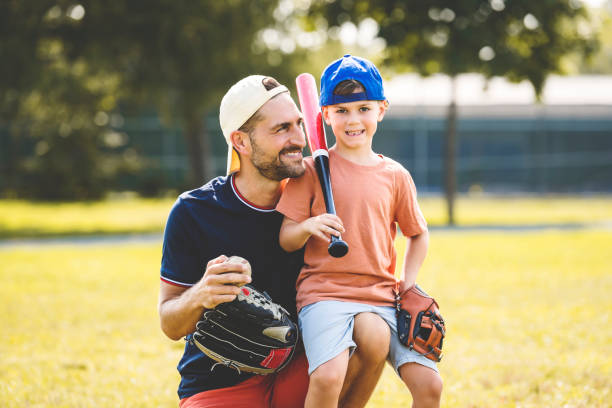 istock Father and son playing baseball in sunny day at public park 1438625363
