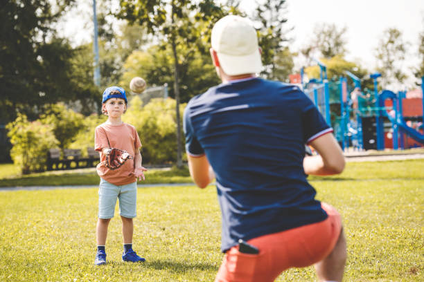 istock Father and son playing baseball in sunny day at public park 1438625663