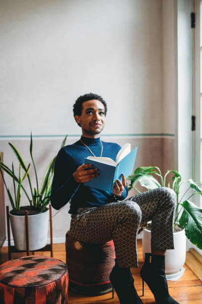 istock A non-binary person is reading a book near the window 1438625955