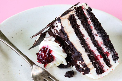 Stock photo showing close-up view of a homemade, luxury, Black Forest gateau displayed on a plate against a pink background.