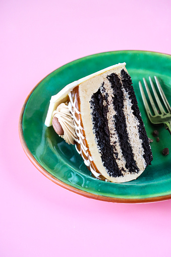 Stock photo showing close-up view of a luxury, coffee and marbled chocolate gateau displayed on a plate against a pink background.