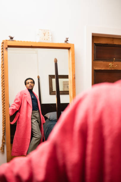 istock A non-binary person is looking at the mirror wearing a pink coat 1438626107