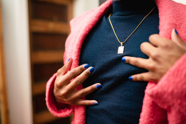 Detail of a non-binary person's hands with nail polish. The person is wearing a pink coat.
