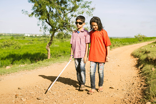 Teenager girl helping to blind brother by walking each other at mountain - concept of caregiver,friendship bonding and disability