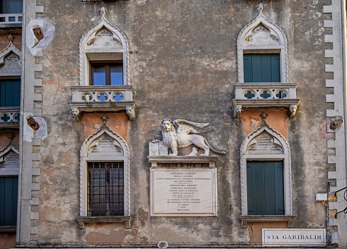 Venice, Italy - October 9th 2022:  The lion of St. Mark is a symbol of the city Venice. This is an old relief on a façade of a palace in the center of the old and famous Italian city Venice