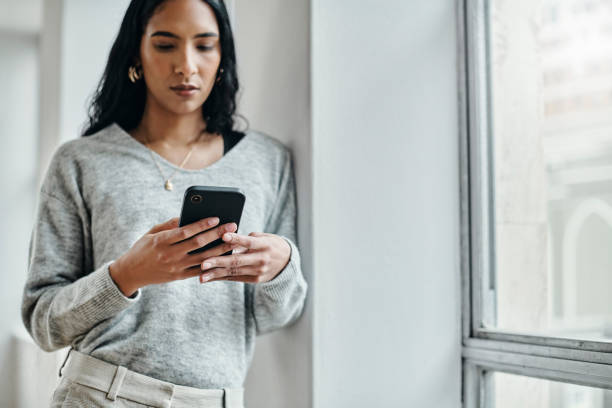 istock Woman, phone and 5g network communication while typing email, social media chat or message by building window for privacy. Female with smartphone while surfing web, internet and mobile app at work 1438628936