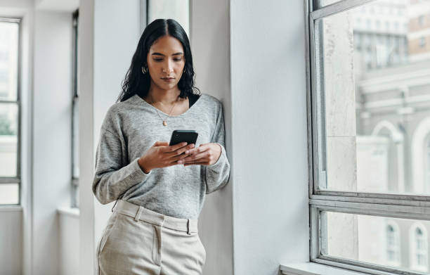 Woman, phone and 5g network communication while typing email, social media chat or message by office window. Female with smartphone while surfing web, internet and mobile app at work
