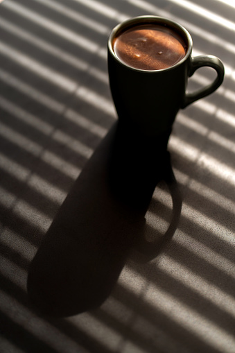 Sunlight Falling On Coffee In Cup On Table