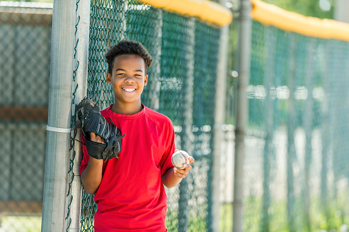 A portrait of child with glove and looking at camera playing baseball